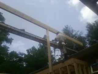 Carpenter setting a ridge beam over a new addition frame — Ice Dam Removal by Roofing Brothers in Brenham