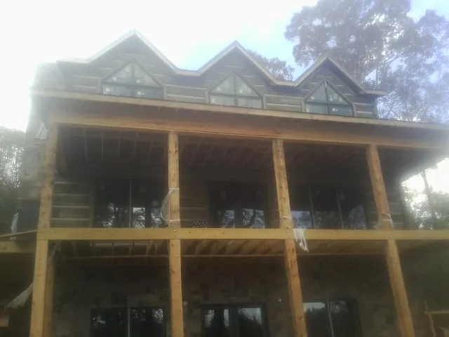 Dormers and porch framing on a large log home under construction — Roof Coating work by our crew in Brenham