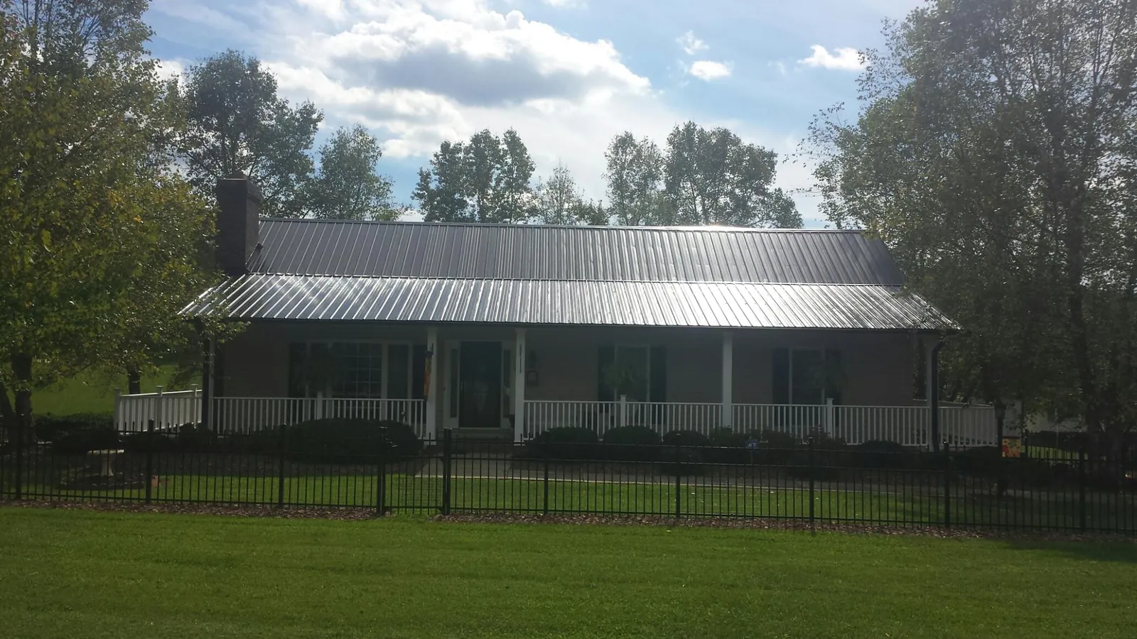 Gray metal roof on a brick ranch with a full width front porch — Gutter Guard Installation work by our crew in Brenham