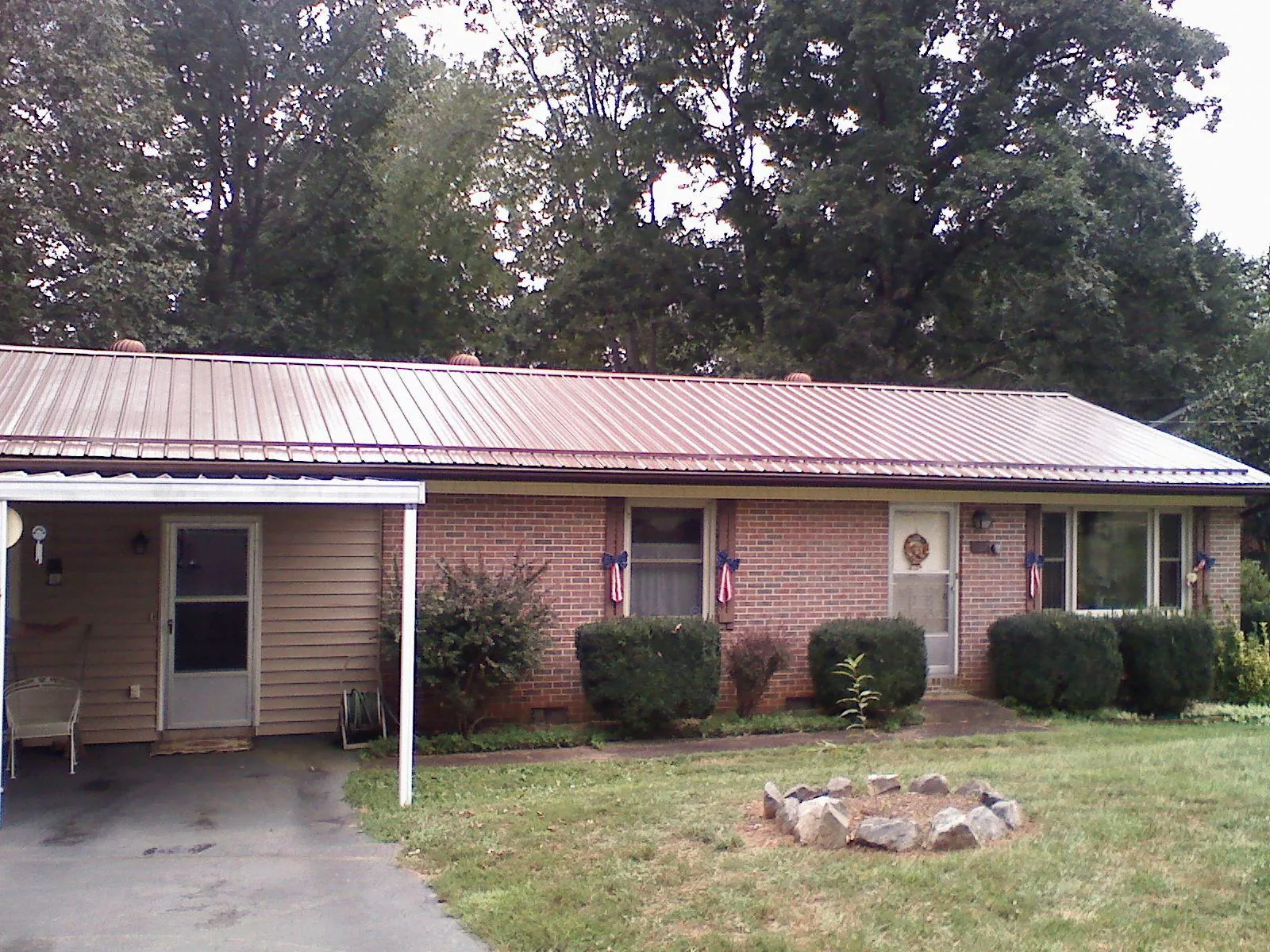 Bronze metal roof and carport on a brick ranch home — Roof Repair work by our crew in Brenham